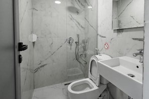 A modern bathroom with a glass-enclosed shower, a toilet, and a sink. - Hotel Aloha (Sarande)