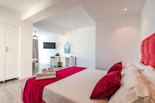 A modern hotel room with a large bed, a desk, and a TV. - Hotel Aloha (Sarande)