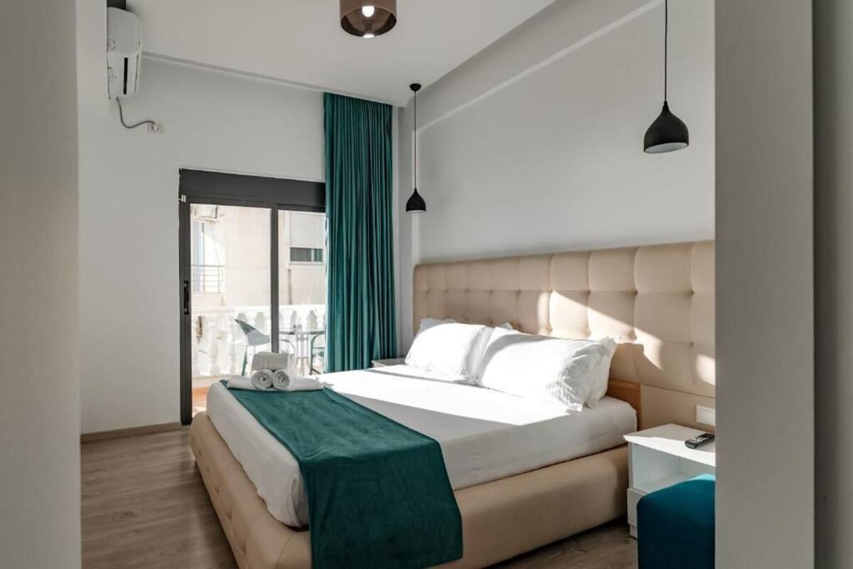 A bedroom with a bed, bedside table, and a view of the outside.