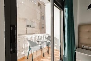 A balcony with a glass door, a small round table, and two chairs. - Hotel Aloha (Sarande)