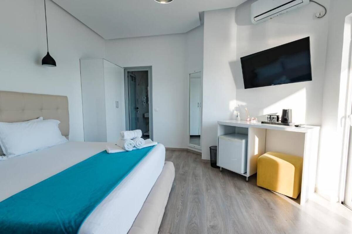 A modern hotel room with a bed, a desk, a TV, and a window.