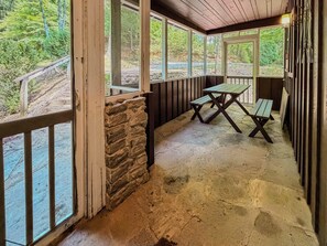 Un espace extérieur abrité, doté de murs en pierre, de bancs en bois et d’une table de pique-nique.