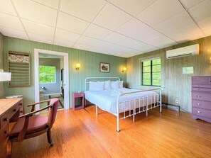 Une chambre à coucher avec un lit, un bureau, une chaise, une commode et une fenêtre.
