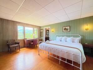 Een slaapkamer met een bed, bureau, stoel en uitzicht op de omgeving.