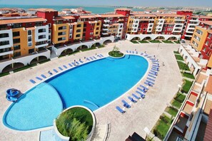 Um hotel com piscina, várias varandas e vista para o mar.