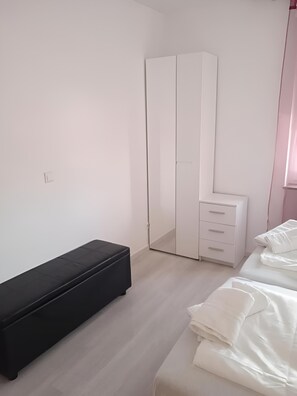 Une chambre à coucher comprenant un lit, un banc, une armoire et une table de chevet.