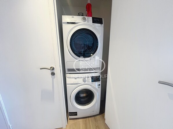A stacked washer and dryer unit in a hallway with a door on the left. - Elegance & Comfort in Cannes Terrace & Parking (Cannes)
