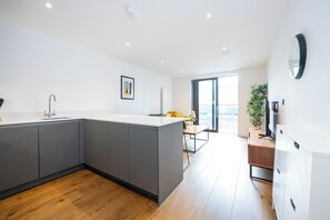 Eine moderne Küche mit grauen Schränken, einer weißen Arbeitsplatte und Holzdielen.