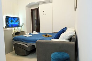 A hotel room with a bed, a TV, a desk, and a chair. - Charming Studio with Stunning Bay Views & Adriatic Soul⁠ (Kriva ulica)