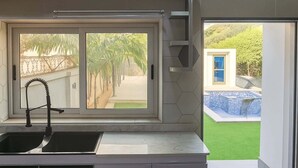 Une cuisine moderne avec une fenêtre, un évier encastré et une vue sur une piscine.