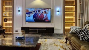 Un salon moderne doté d’un grand téléviseur à écran plat, d’une table basse en marbre, d’un canapé en cuir et d’appliques murales.