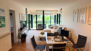 A modern living room with a sofa, a dining table with chairs, a TV, and artwork on the walls. - Villa 'Isabelle' with Shared Pool, Private Terrace and Wi-Fi (Navata)