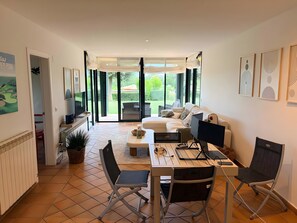Ein modernes Wohnzimmer mit einer Couch, einem Esstisch mit Stühlen, einem Fernseher und Kunstwerken an den Wänden.