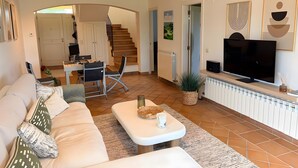 A living room with a sofa, a coffee table, a TV, and a staircase leading to another room. - Villa 'Isabelle' with Shared Pool, Private Terrace and Wi-Fi (Navata)