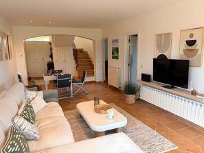 Ein Wohnzimmer mit einer Couch, einem Couchtisch, einem Fernseher und einer Treppe, die in einen anderen Raum führt.