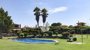 A residential area with a swimming pool, well-maintained lawns, and a variety of trees. - Villa 'Isabelle' with Shared Pool, Private Terrace and Wi-Fi (Navata)