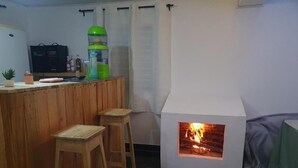 Ein gemütlicher Raum mit einer Holztresorecke, einem kleinen Kamin und einem Fernseher.