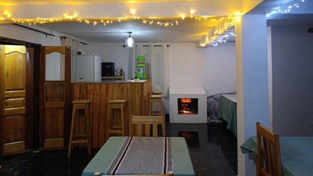 Ein gemütlicher Raum mit Esstisch, Holzstühlen, einer Bar und einem Kamin.