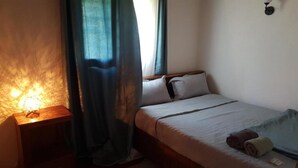 Ein Schlafzimmer mit einem Bett, einem Nachttisch, einer Lampe und einem Fenster mit Vorhängen.