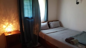 A bedroom with a bed, a nightstand, a lamp, and a window with curtains.