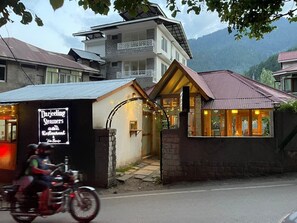 Een gebouw met een bord voor Darjeeling Steamers Restaurant & Tea House, een stenen entree en een berg op de achtergrond.