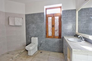 A bathroom with a toilet, sink, and window with a view. - The Red House (Manali)