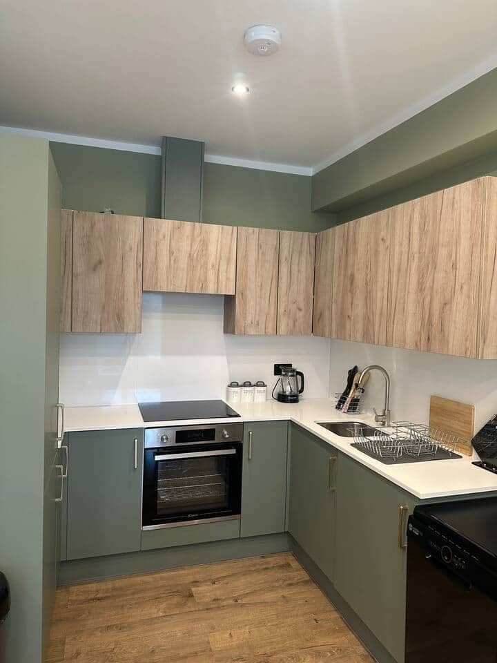 A compact kitchen with a built-in oven, a sink, and wooden cabinets.