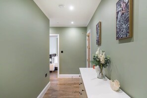 Ein Flur mit einer weißen Theke, einem Blumenstrauß und gerahmten Kunstwerken an der Wand.