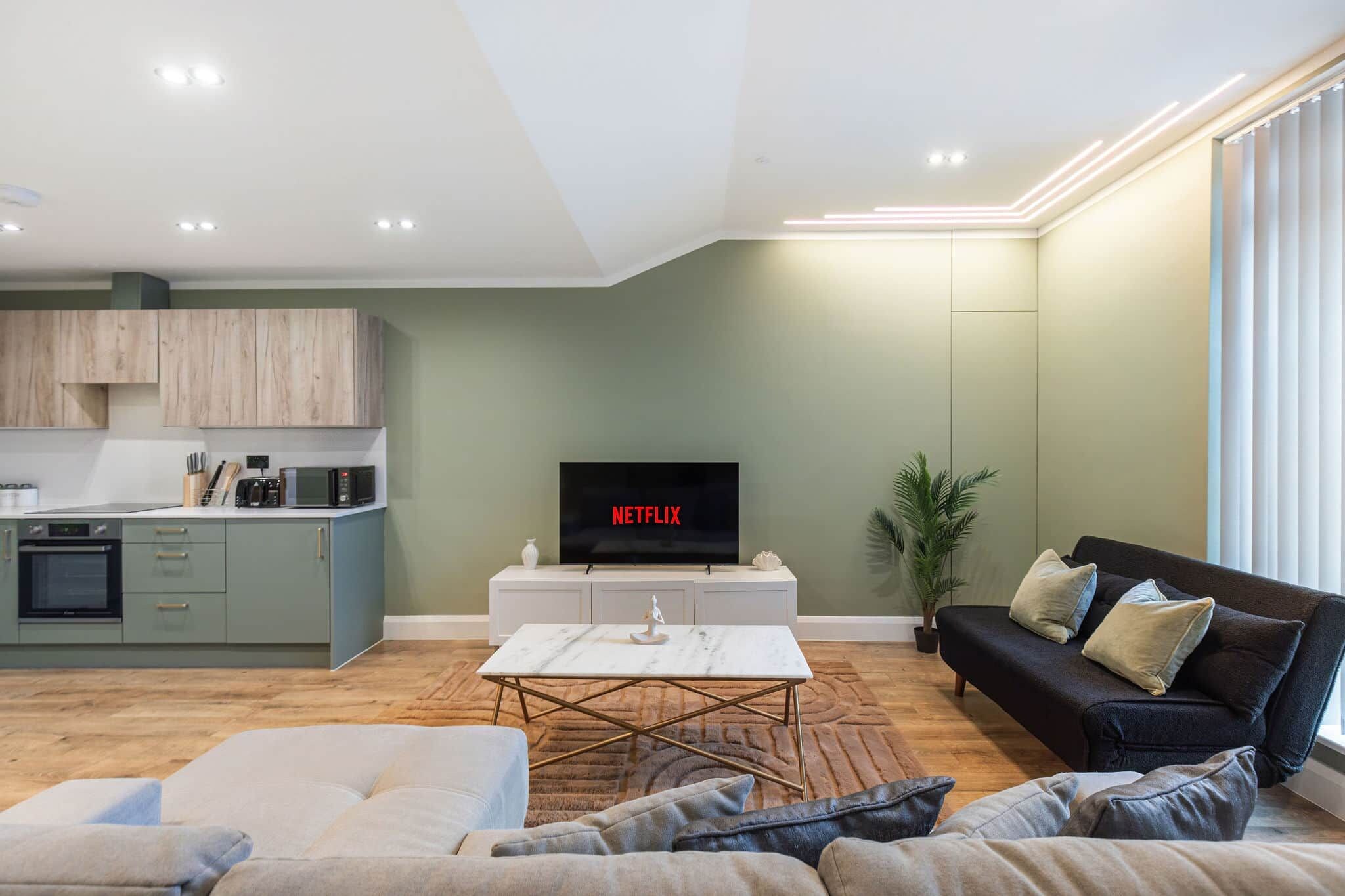A modern living room with a sofa, a coffee table, and a TV displaying 'NETFLIX'.