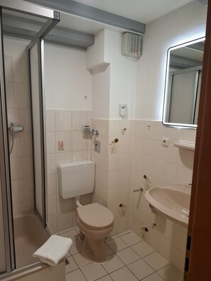 Ein Badezimmer mit Toilette, Waschbecken, Dusche und Spiegel.