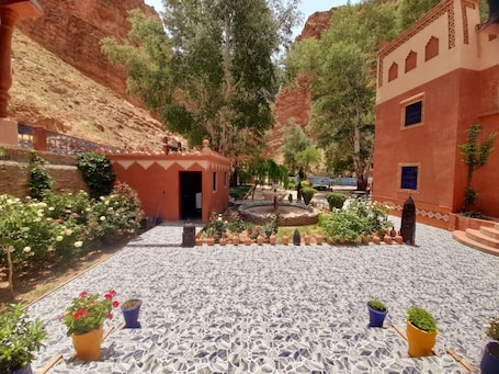 A courtyard with a fountain, potted plants, and a tiled floor.. Berbere De La Montagne Hotel