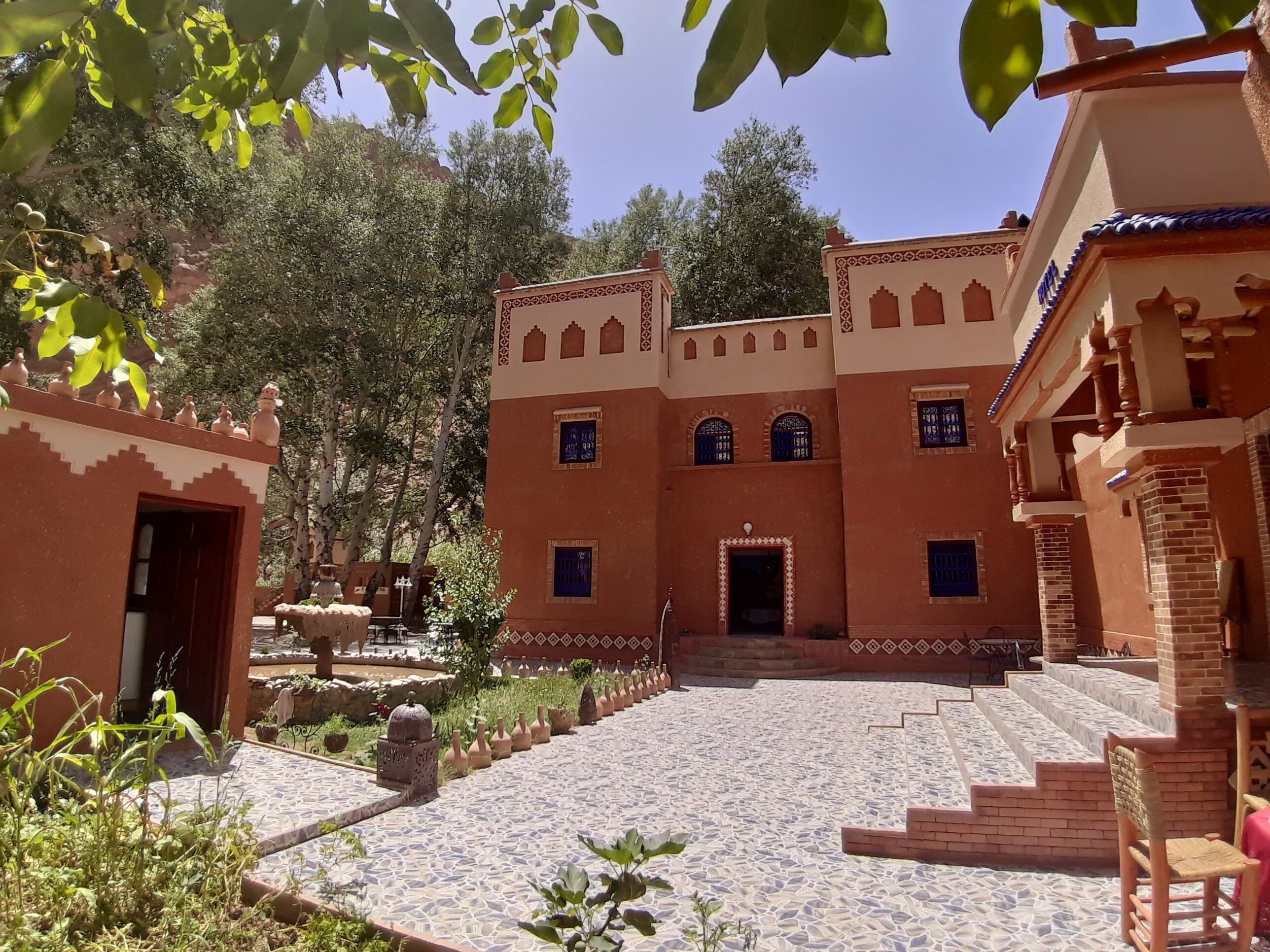 A courtyard with a patterned floor, traditional architecture, and a staircase leading to the entrance.