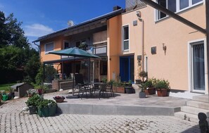 A building with a patio area, outdoor seating, and potted plants.