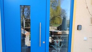 Una porta blu con un vetrino, una maniglia in metallo e una cassetta delle lettere a parete.