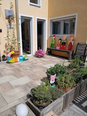 A courtyard with potted plants, a bench, and a wall-mounted sculpture of a pig.