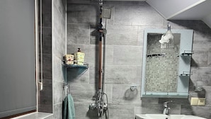 Un baño moderno con ducha, lavamanos y espejo.