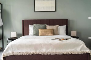 A neatly made bed with a white bedspread and a dark headboard, accompanied by two bedside tables with lamps. - Stylish Studio l Balcony l No Elevator (Athens)