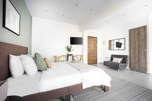 A modern bedroom with a large bed, a flat-screen TV, a small round table with chairs, a sofa, and a wardrobe. - Stylish Studio l Balcony l No Elevator (Athens)