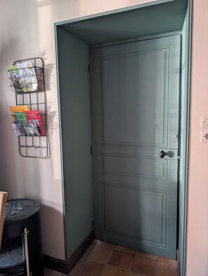 Eine geschlossene Tür mit einem Metallregal, an dem Bücher an der Wand hängen.