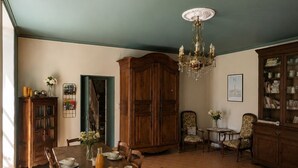 Une salle à manger avec une longue table en bois, des chaises, un lustre et un buffet aux portes vitrées.