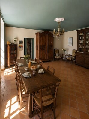 A dining room with a long wooden table, chairs, a chandelier, and a cabinet with glass doors. - Vrbo Property (Vervant)