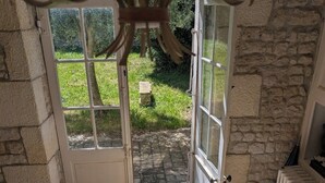 Une pièce avec un mur en pierre, un radiateur blanc et une porte donnant sur un jardin.