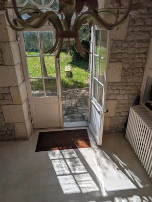 Ein Zimmer mit Steinwand, einem weißen Heizkörper und einer Tür, die in einen Garten führt.