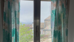 A window with a view of a stone wall and greenery outside. - Charming town house located in the beautiful historic village of Casalanguida. (Casalanguida)