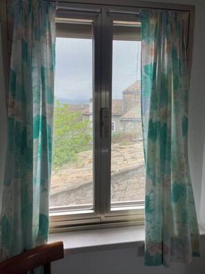 A window with a view of a stone wall and greenery outside. - Charming town house located in the beautiful historic village of Casalanguida. (Casalanguida)