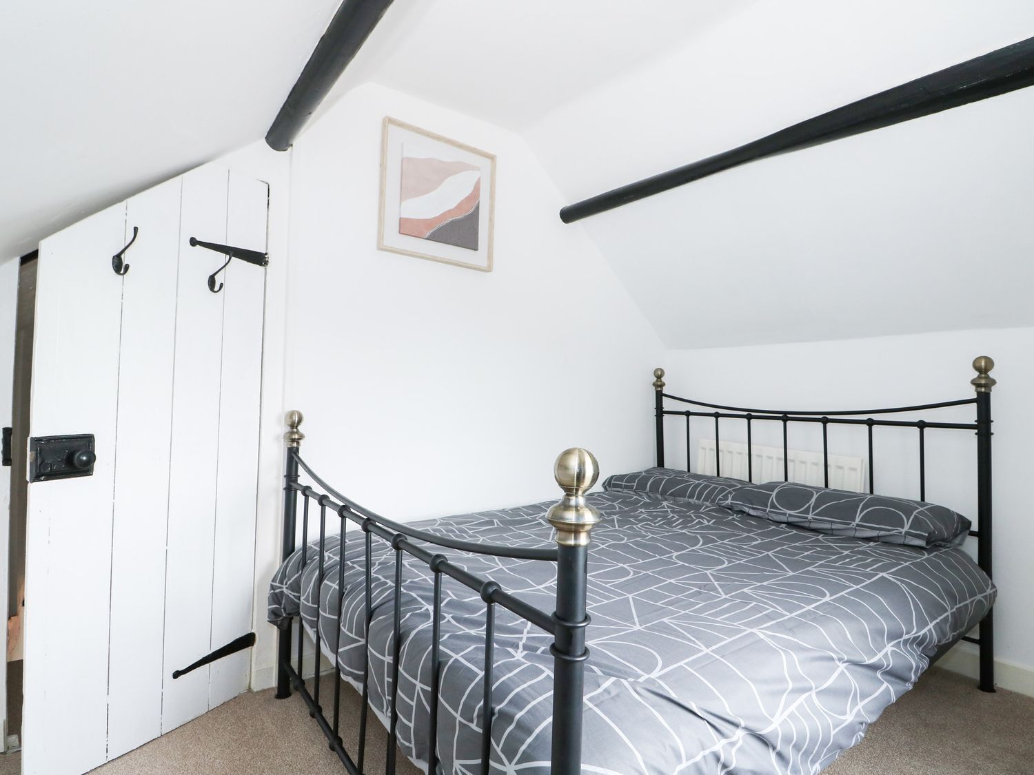 Ein Schlafzimmer mit einem Bett, einer Tür und einem Bild an der Wand.
