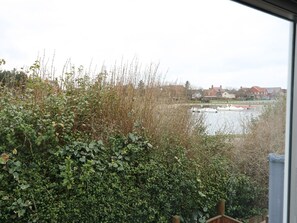 A view of a river with boats, surrounded by dense greenery and houses in the background. - Oar Cottage (Mablethorpe)