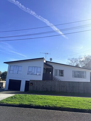 En tvåvåningsbyggnad med ett garage, en satellantenn och ett trästaket.