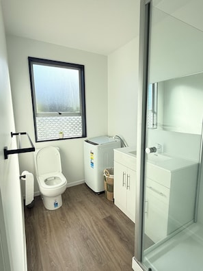 Ein Badezimmer mit Toilette, Waschmaschine, Waschbecken und einem Fenster mit Blick auf den Strand.