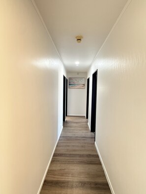A hallway with white walls, a wooden floor, and black doors. - Virginia Lake Family Retreat (Whanganui)